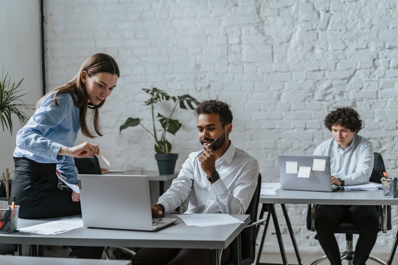 A group of professionals collaborating in a modern office setting, engaging with technology and teamwork.