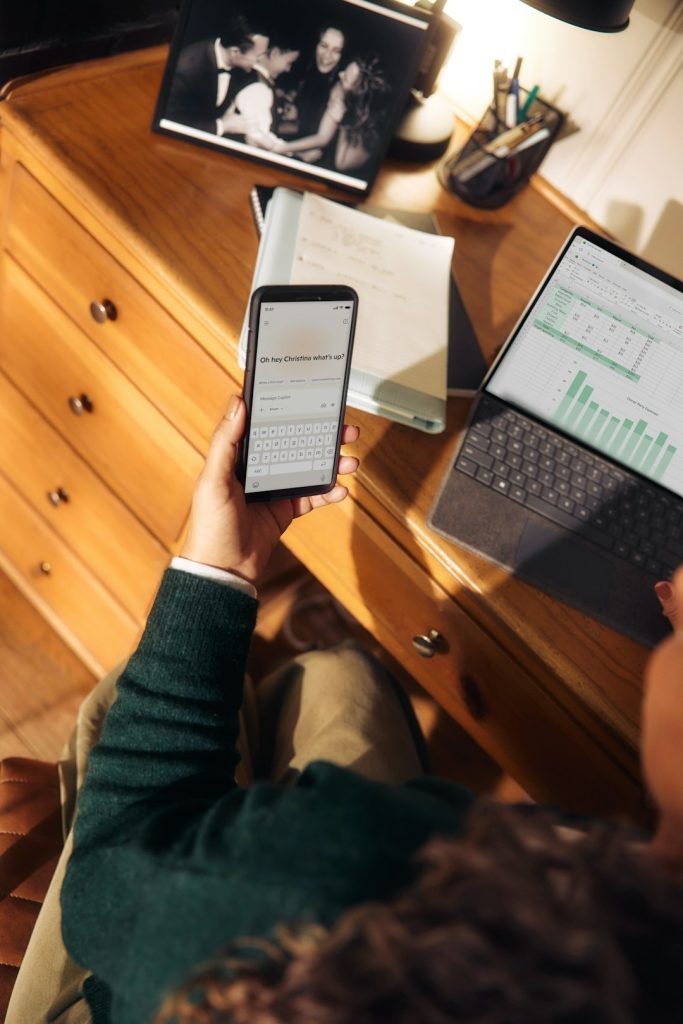 person-holding-phone-near-laptop-and-tablet-on-desk-7r3pqlcvnzq